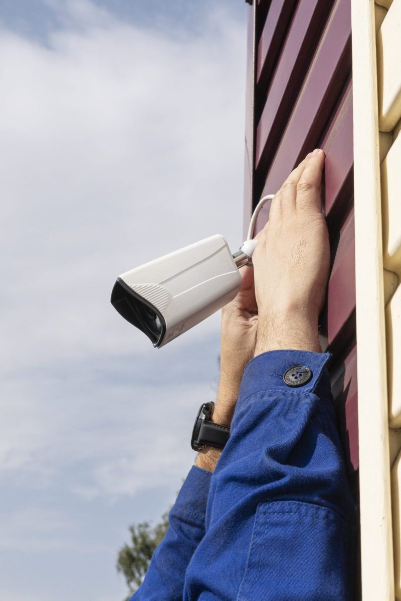 Technician worker installing video surveillance camera. CCTV camera closeup. A video surveillance camera in the hands of a technician. Installation of outdoor video surveillance in close-up.